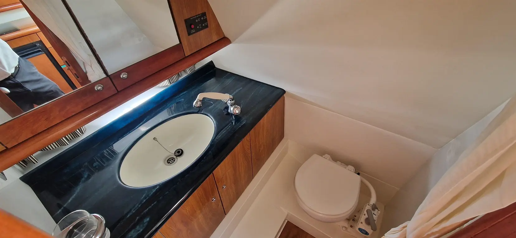 Modern yacht bathroom featuring a circular sink, chrome taps, wooden cabinetry, and a compact toilet.